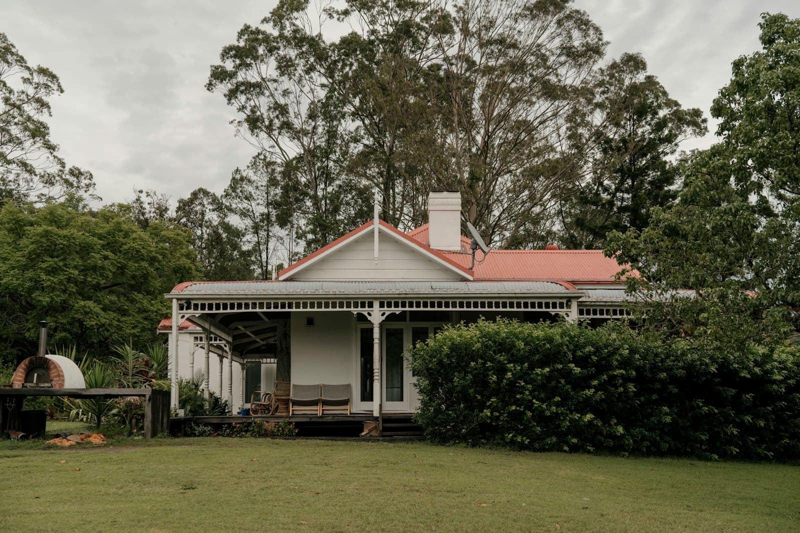 Weatherboard home with a red roof surrounded by tall gum trees